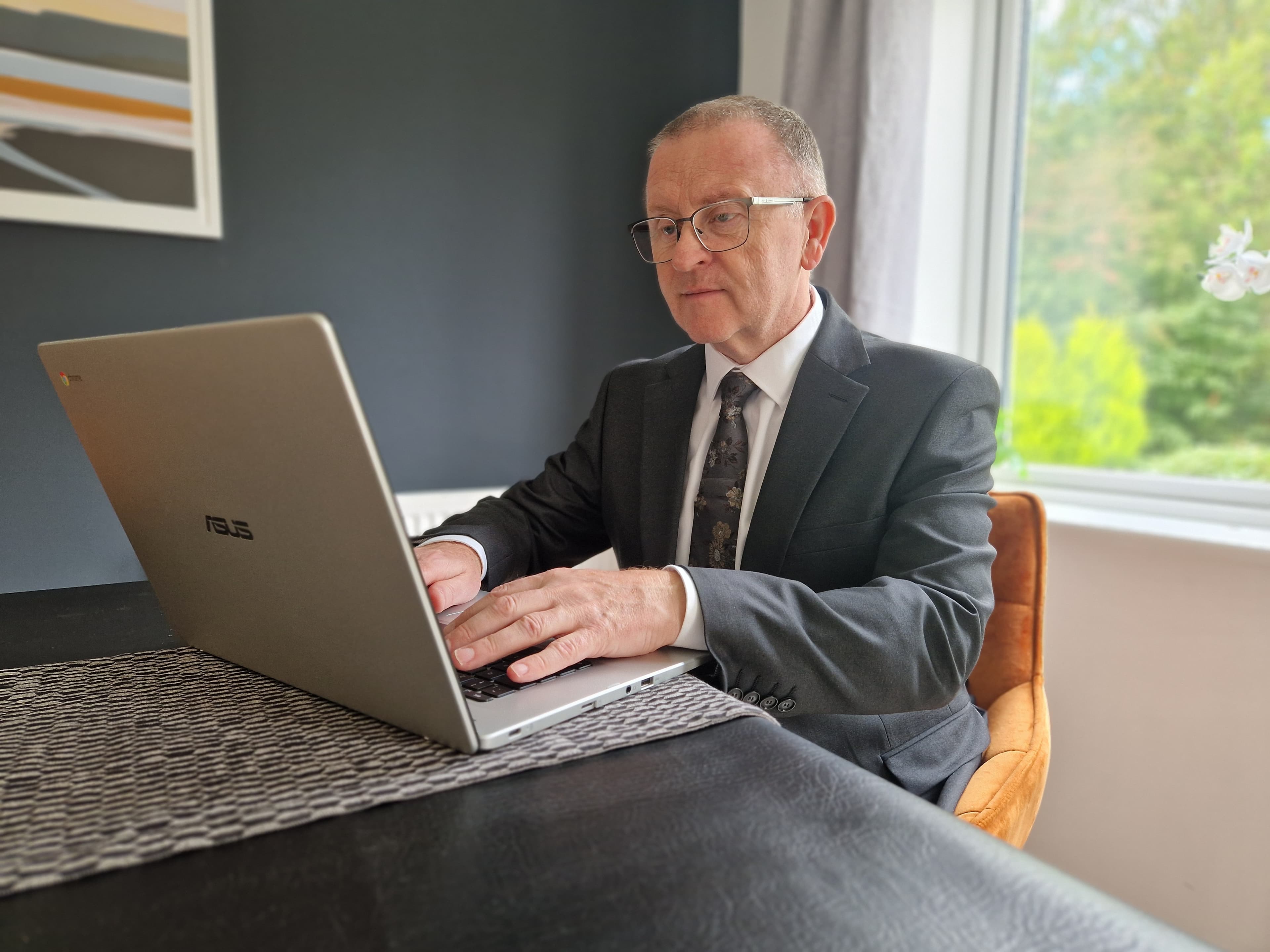 A professional man working on a laptop at a table.